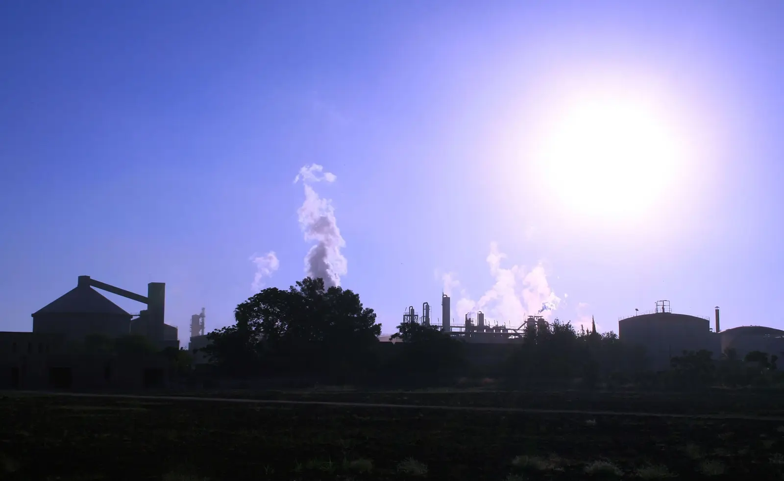 Silueta de la azucarera de San José de La Rinconada al amanecer, con columnas de vapor sobre un campo arado